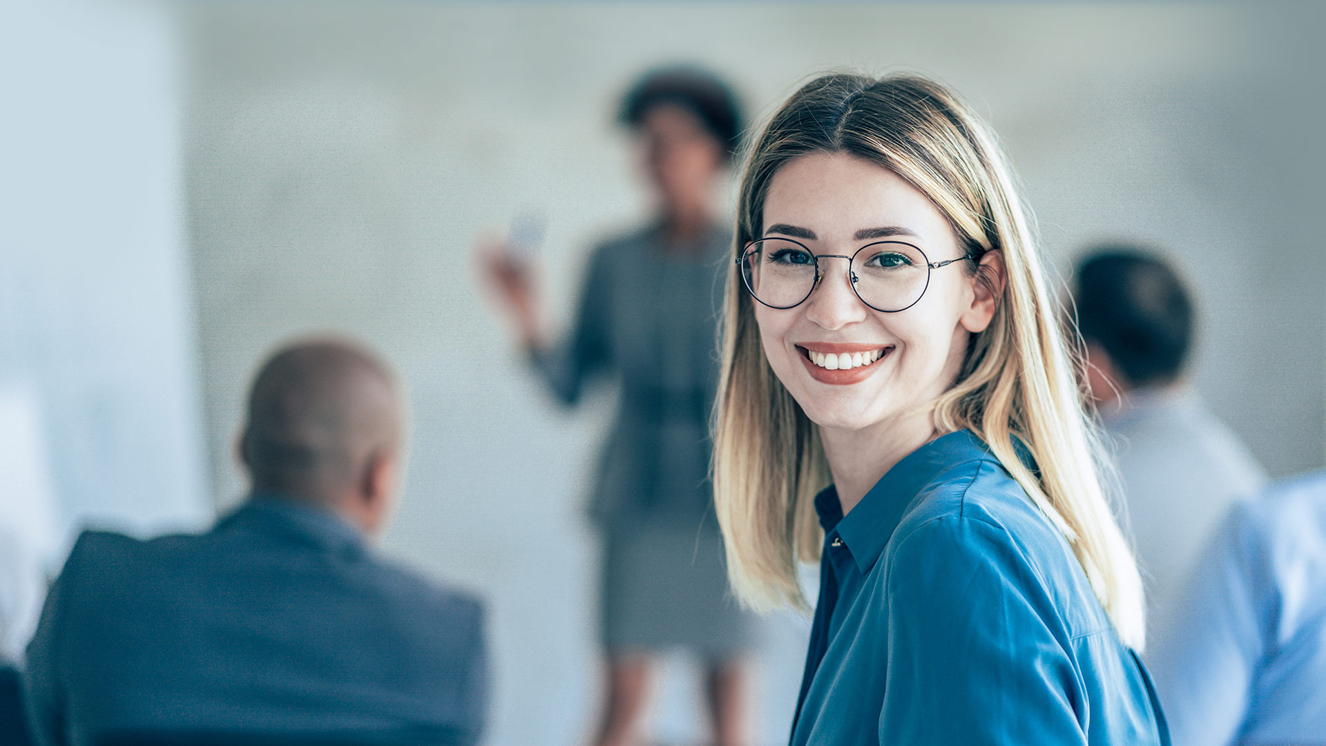 A woman smiles at the camera during a meeting