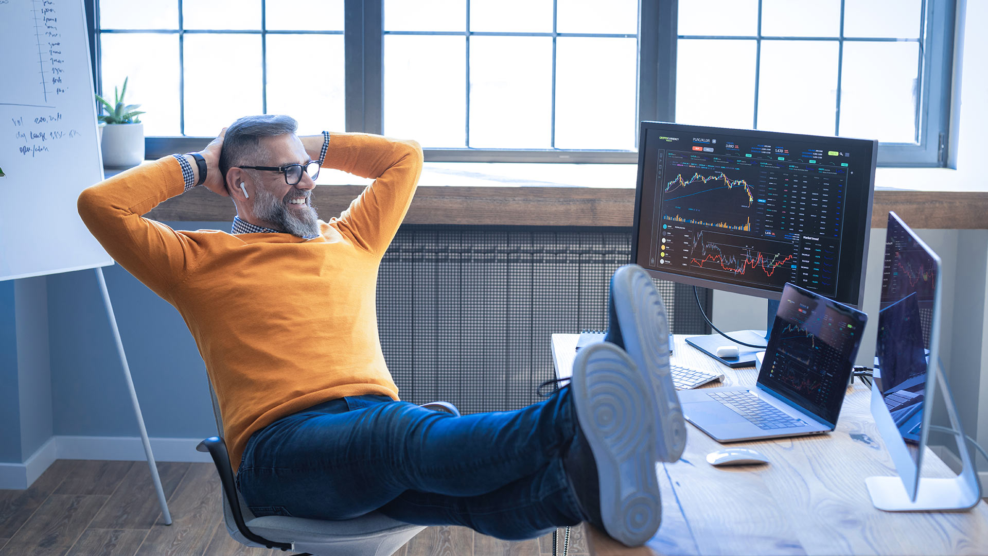 Employee sits in front of several screens with financial charts