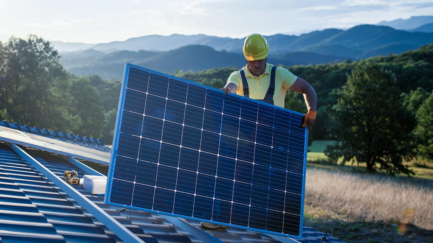 Mann installiert Solaranlage auf einem Dach