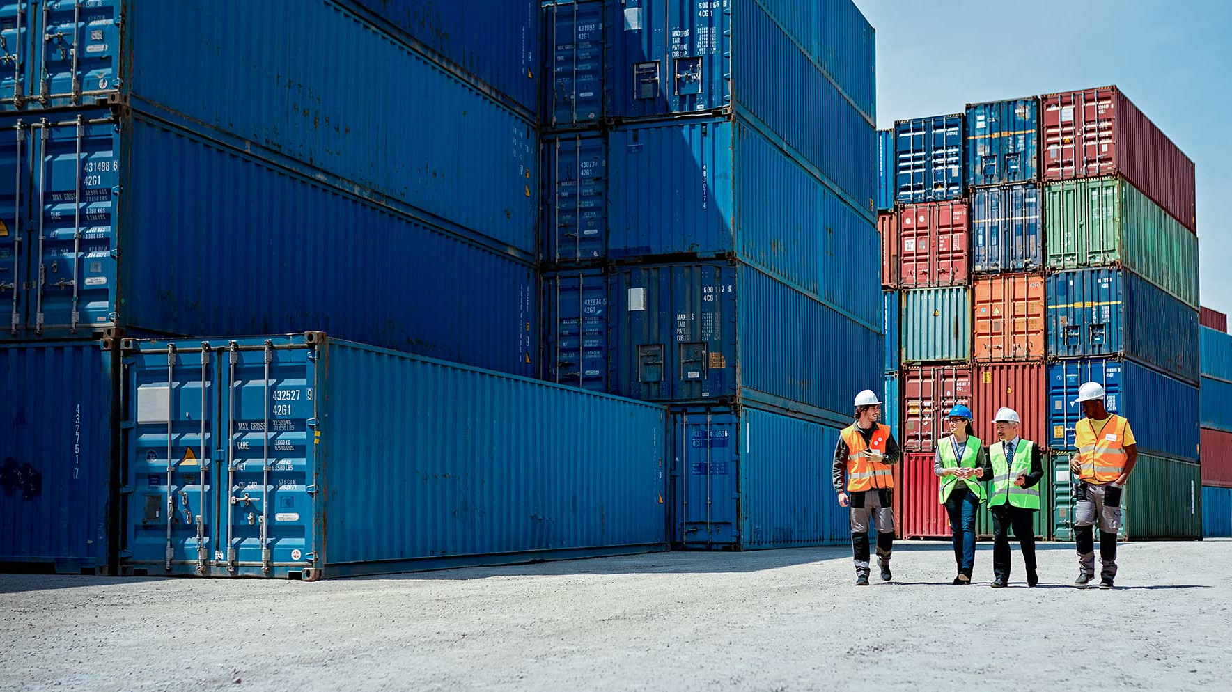 Employees walk between containers in the port