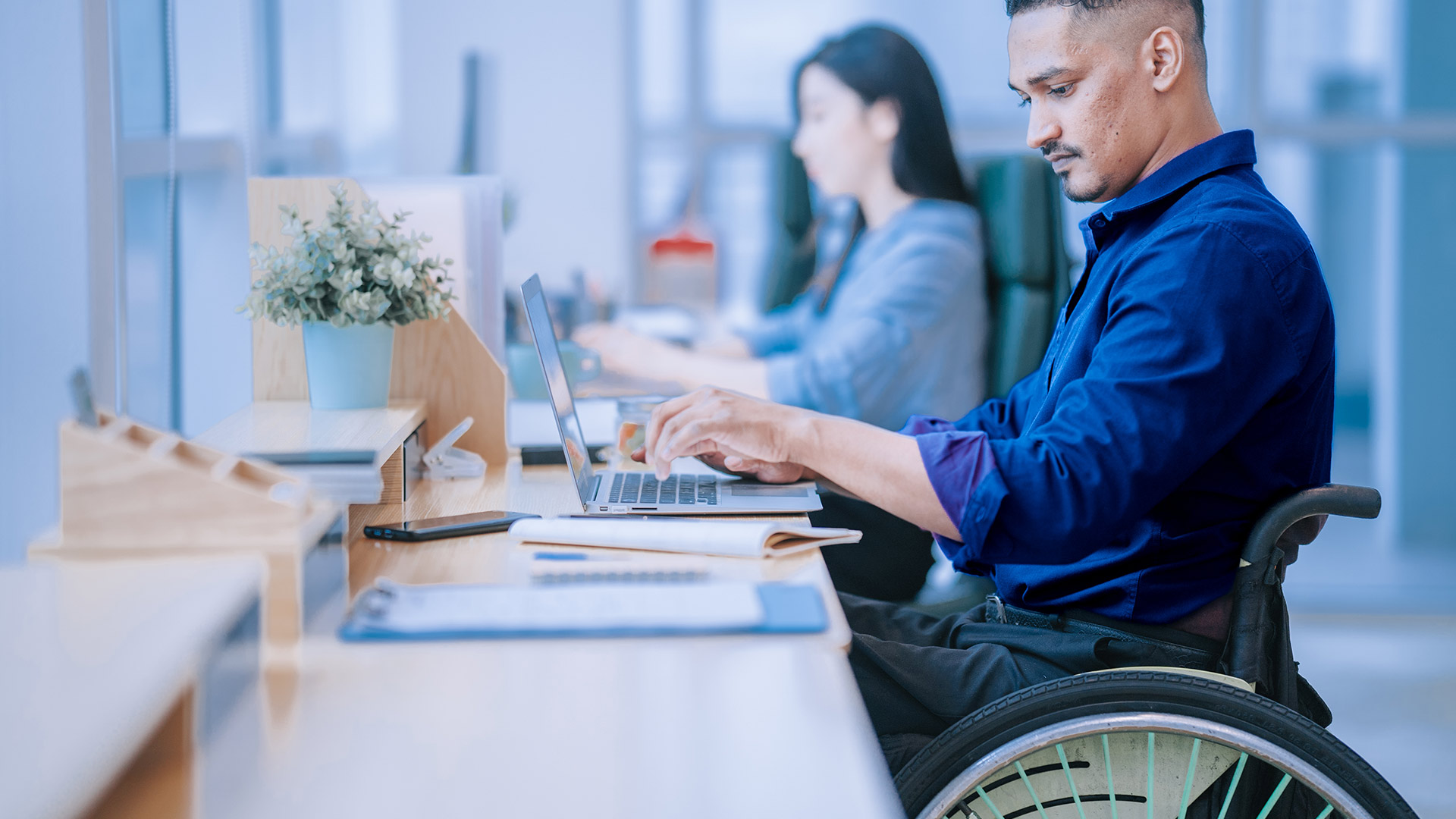 Man in wheelchair sitting at desk in office