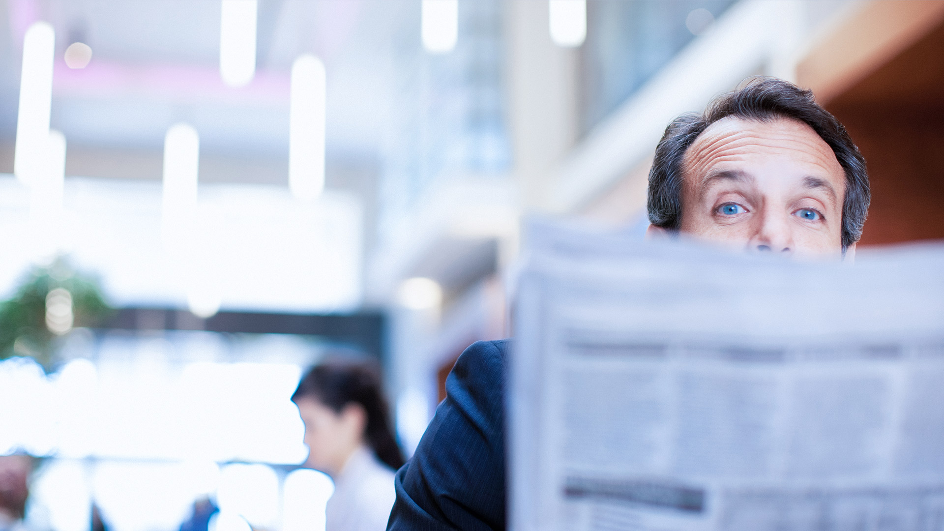 A man looks out from behind a newspaper