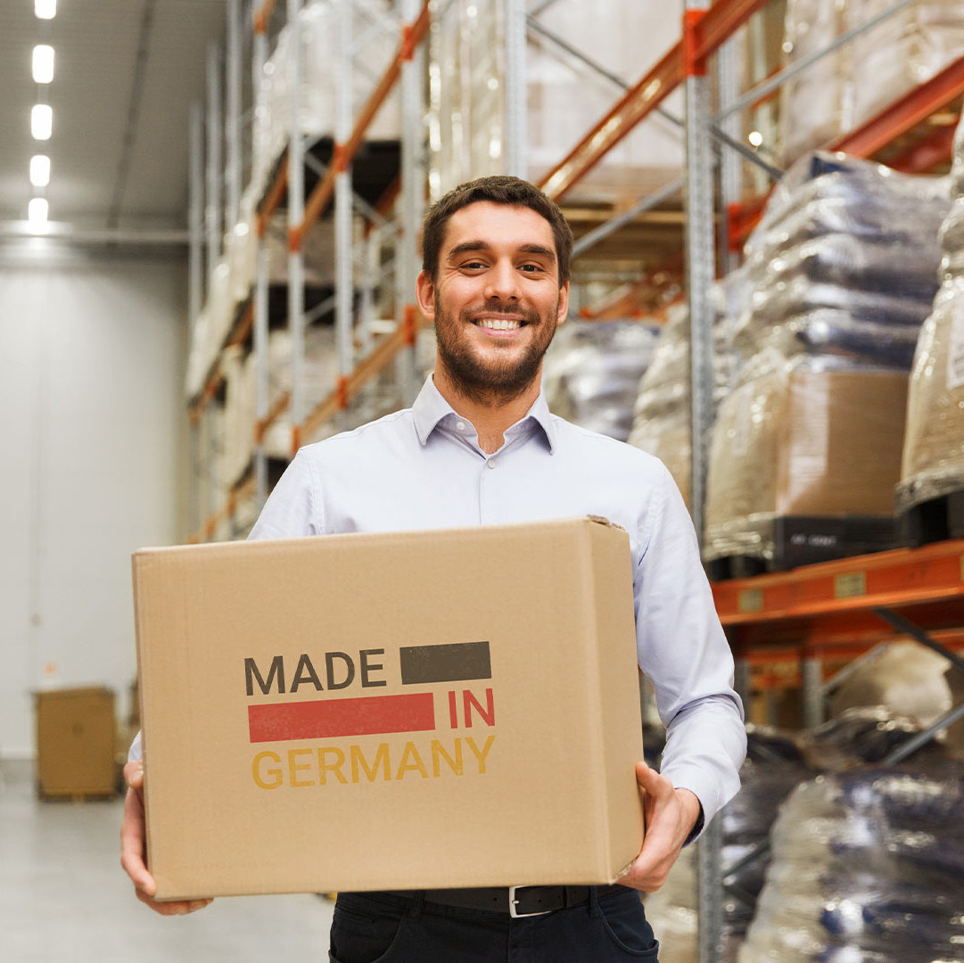 Employé debout dans un entrepôt avec une boîte « Made in Germany »