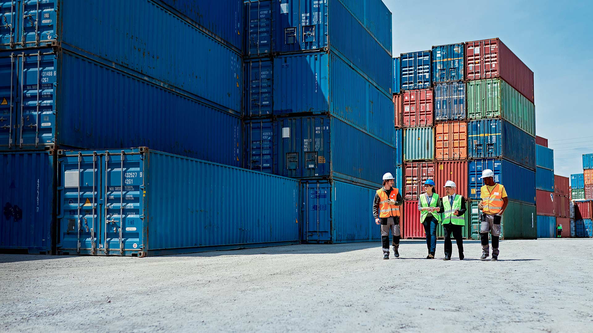 Instrumente der Außenwirtschaftsförderung | Exportkreditgarantien des Bundes Mitarbeiter gehen über einen Containerstellplatz im Hafen