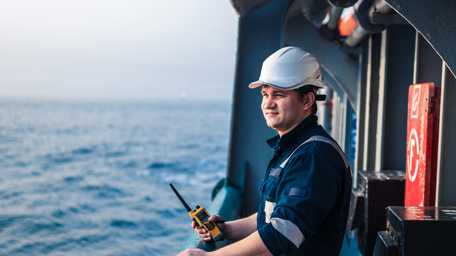 Ship employee stands with a radio on a ship at sea