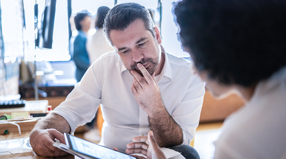 An employee discusses content on a tablet with a colleague