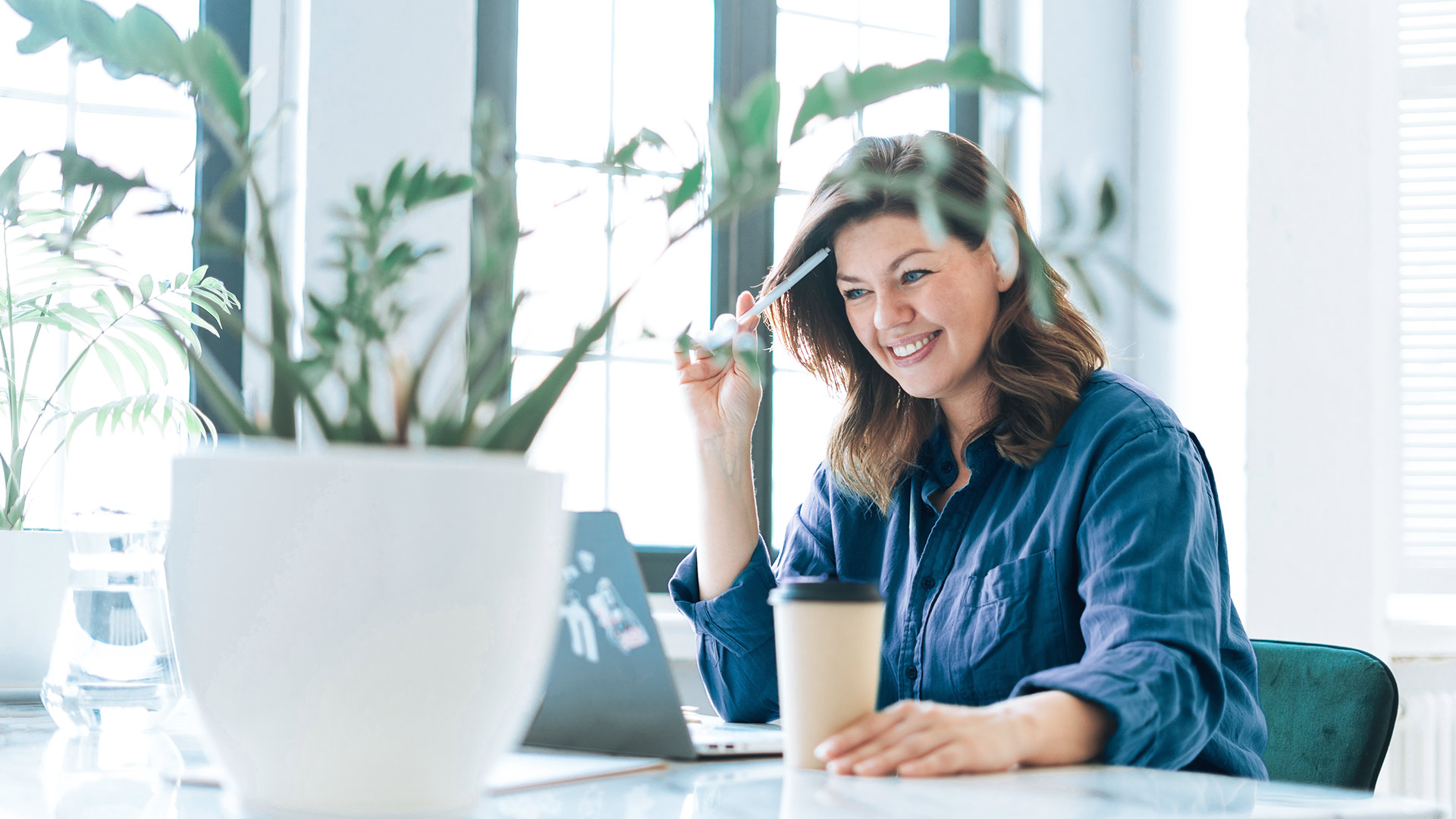 A woman sits smiling in front of a laptop