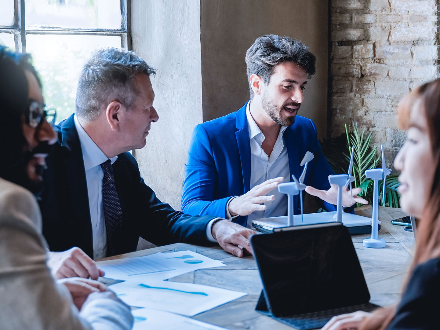 An employee explains models of a wind turbine in a meeting