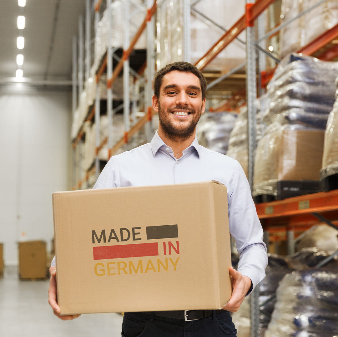 Empregado em pé em um armazém com uma caixa "Made in Germany"