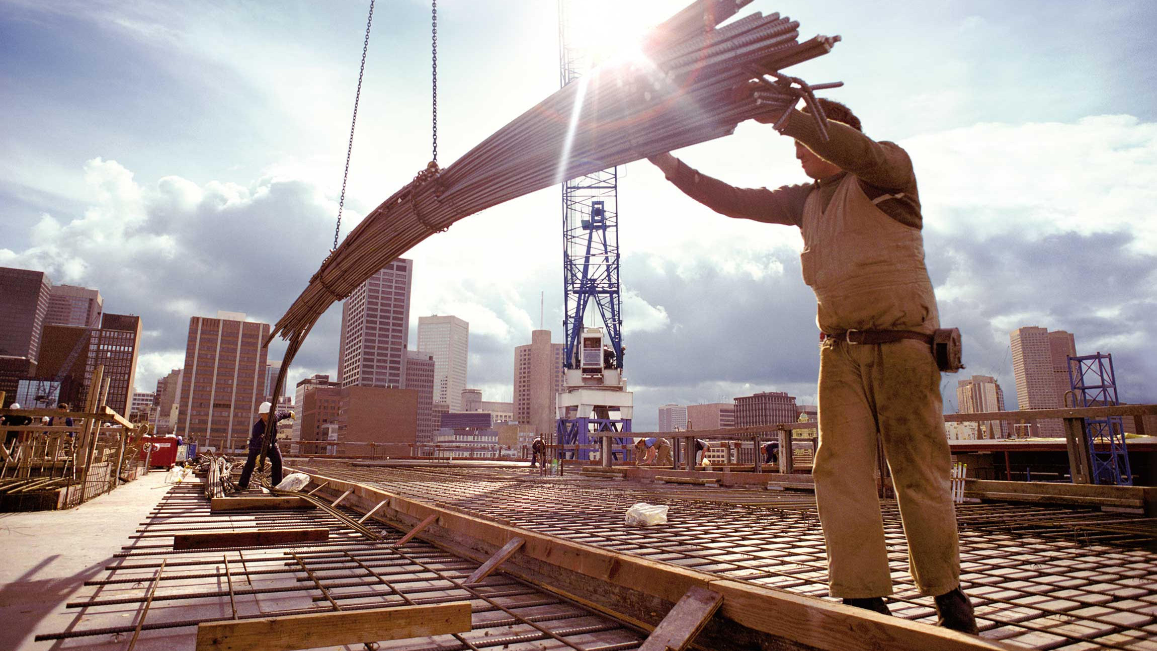 Bauarbeiter lässt Stahlteile an einem Kran herunter