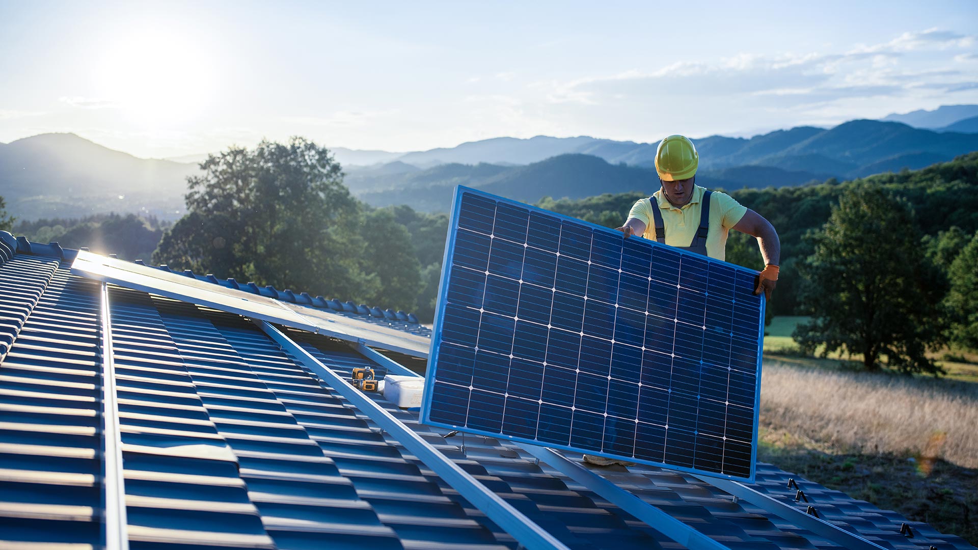 A worker installs a solar panel on a roof