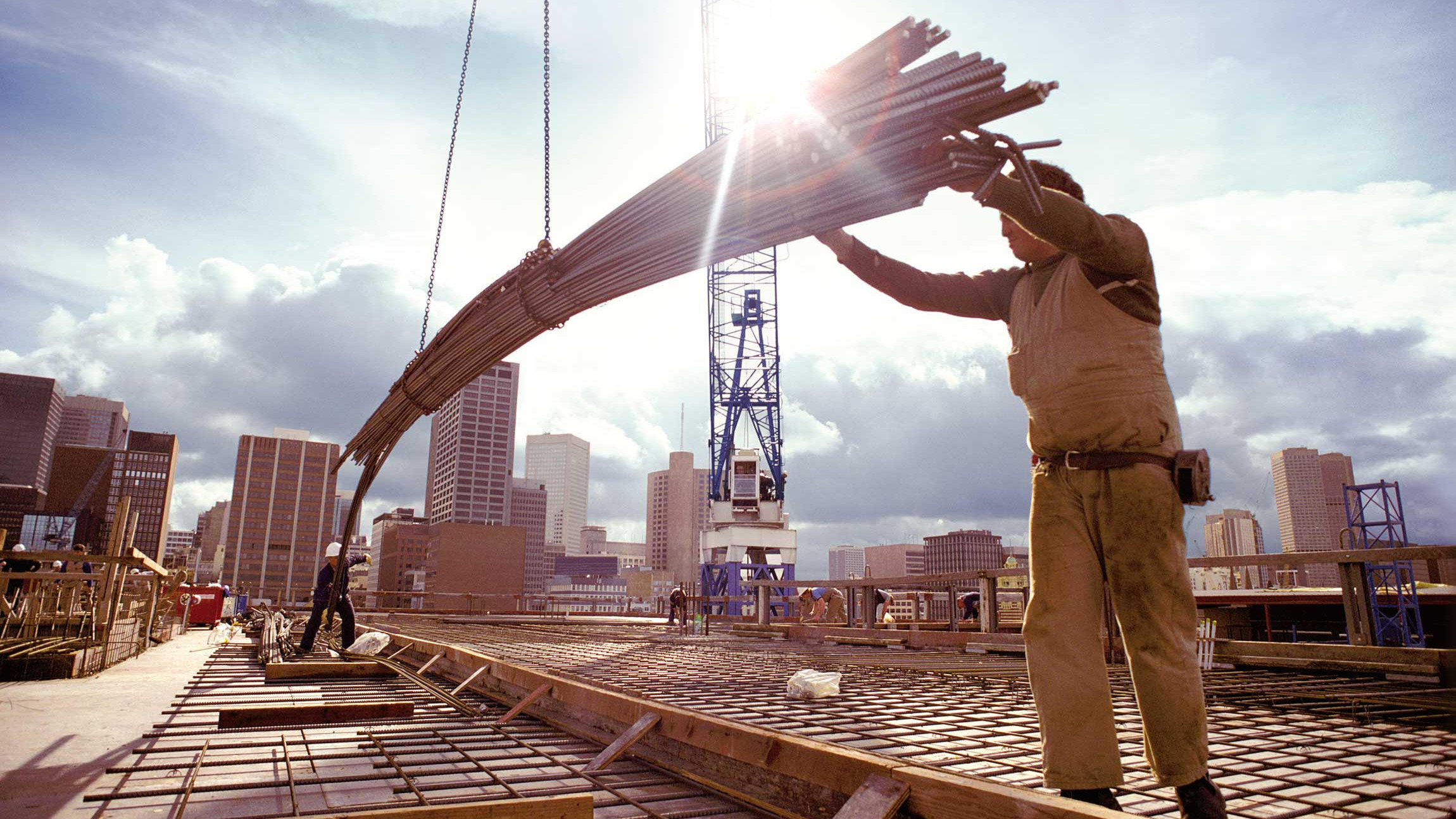 Construction worker lowers steel parts on a crane