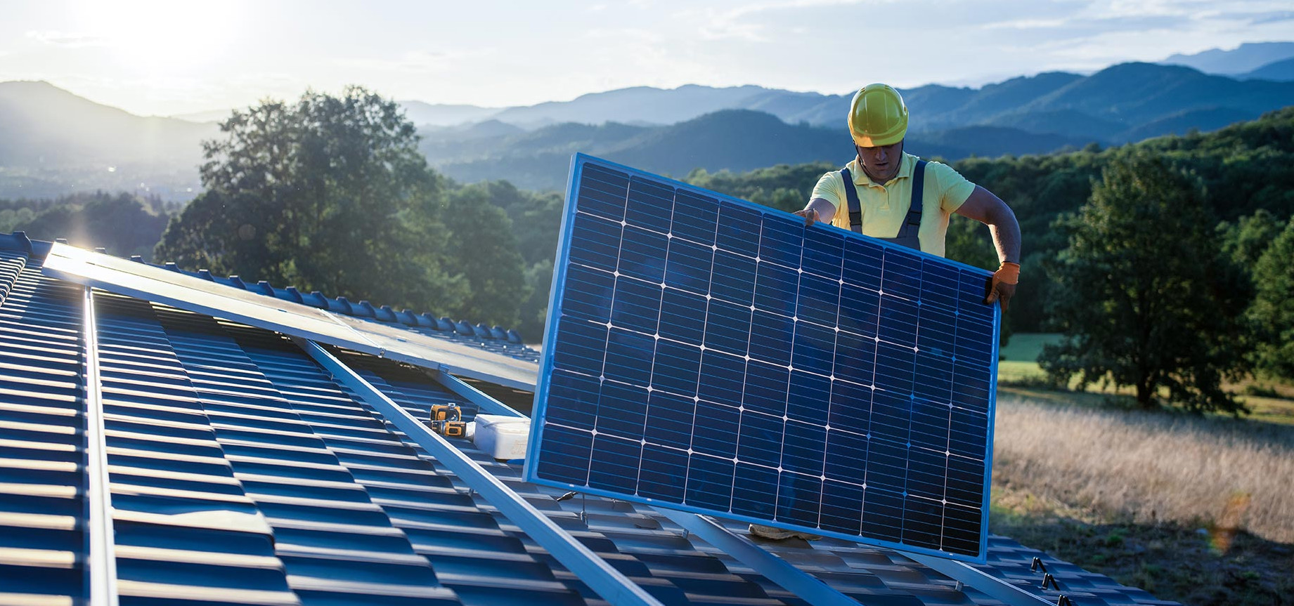 Image: Man with solar panel in hand on the roof Image: Man with solar panel in hand on the roof