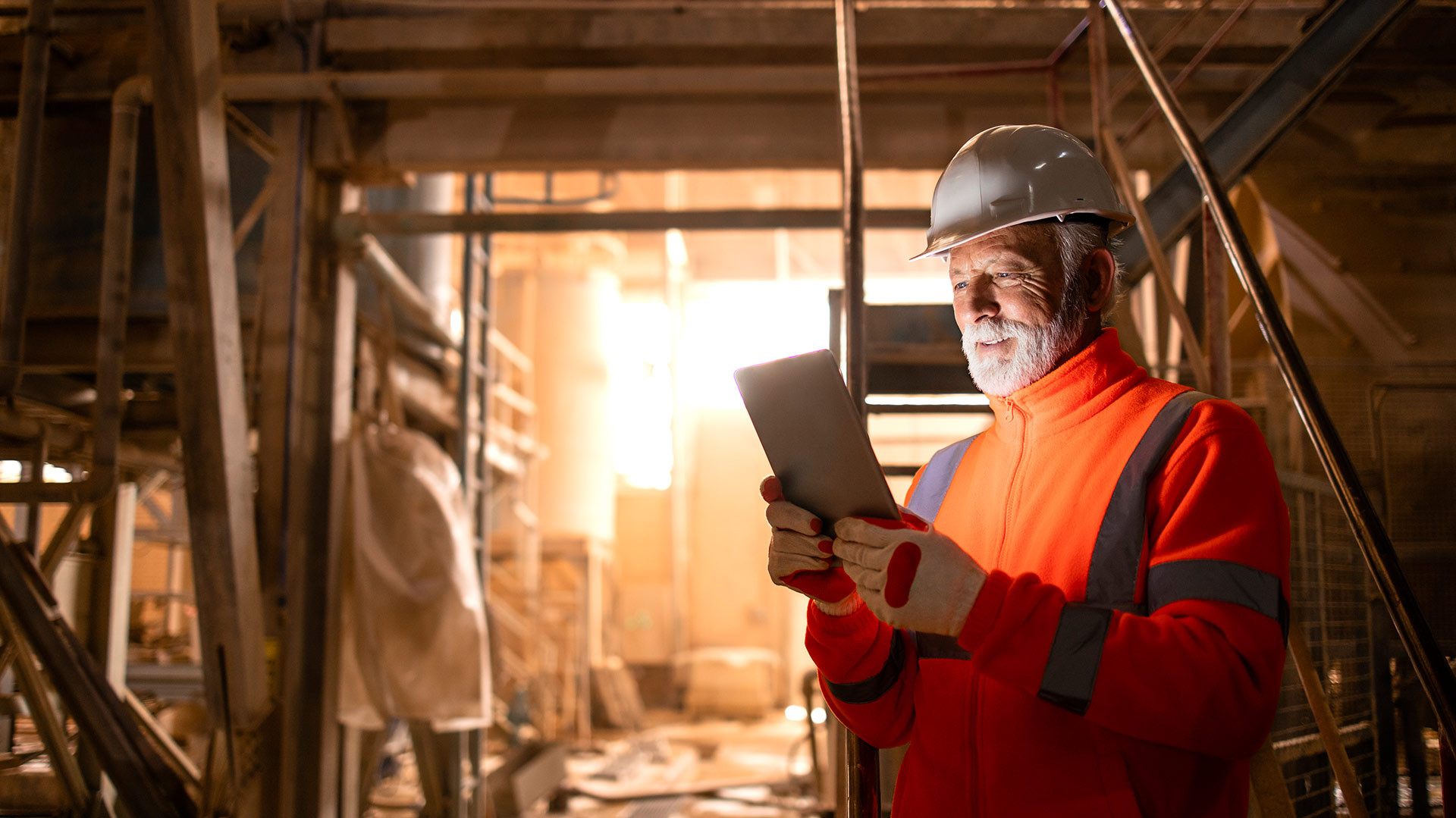 Bild: Mann in Schutzkleidung liest auf dem Tablet in Fabrikhalle