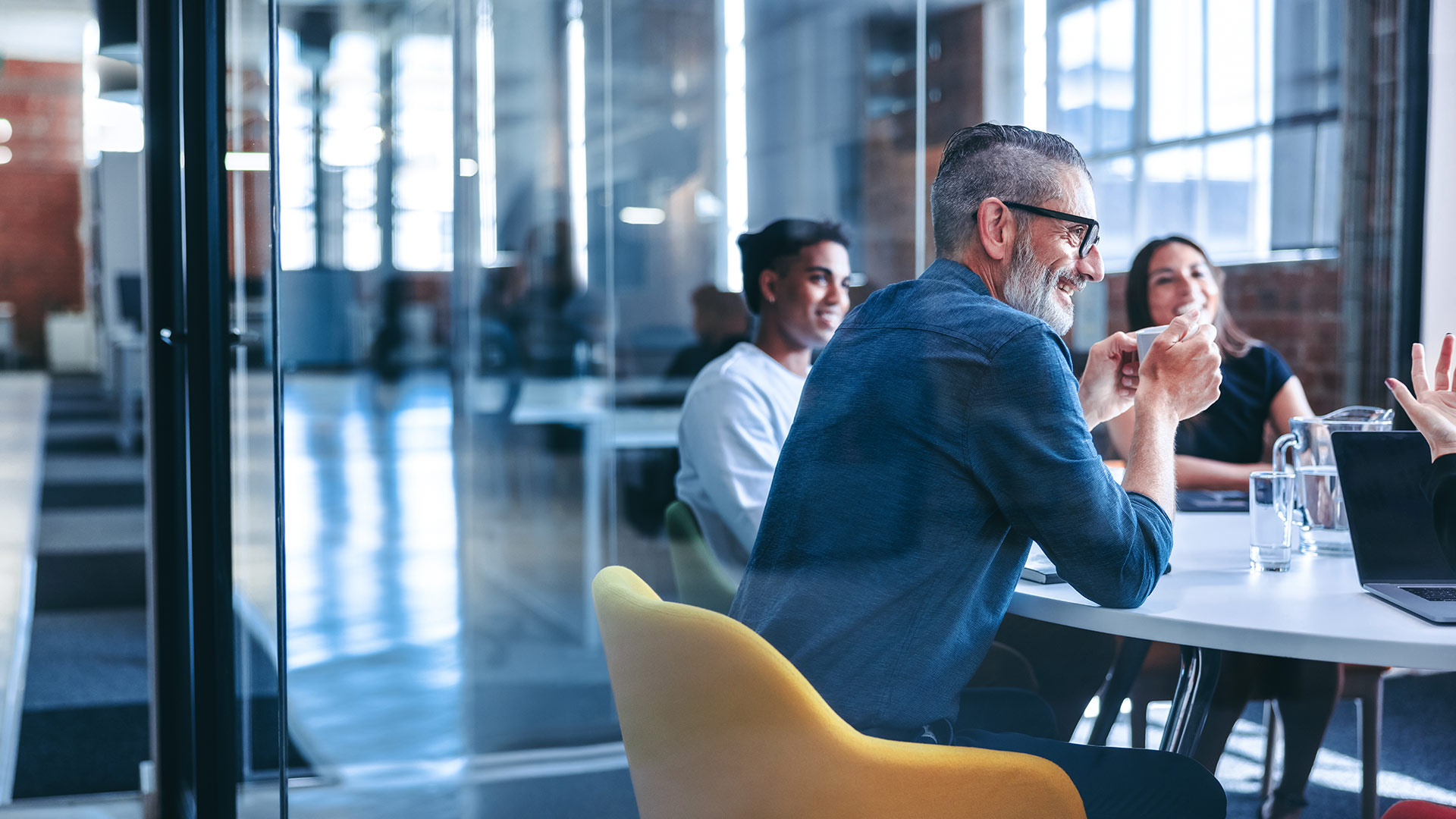 Several people are sitting in a glass meeting room